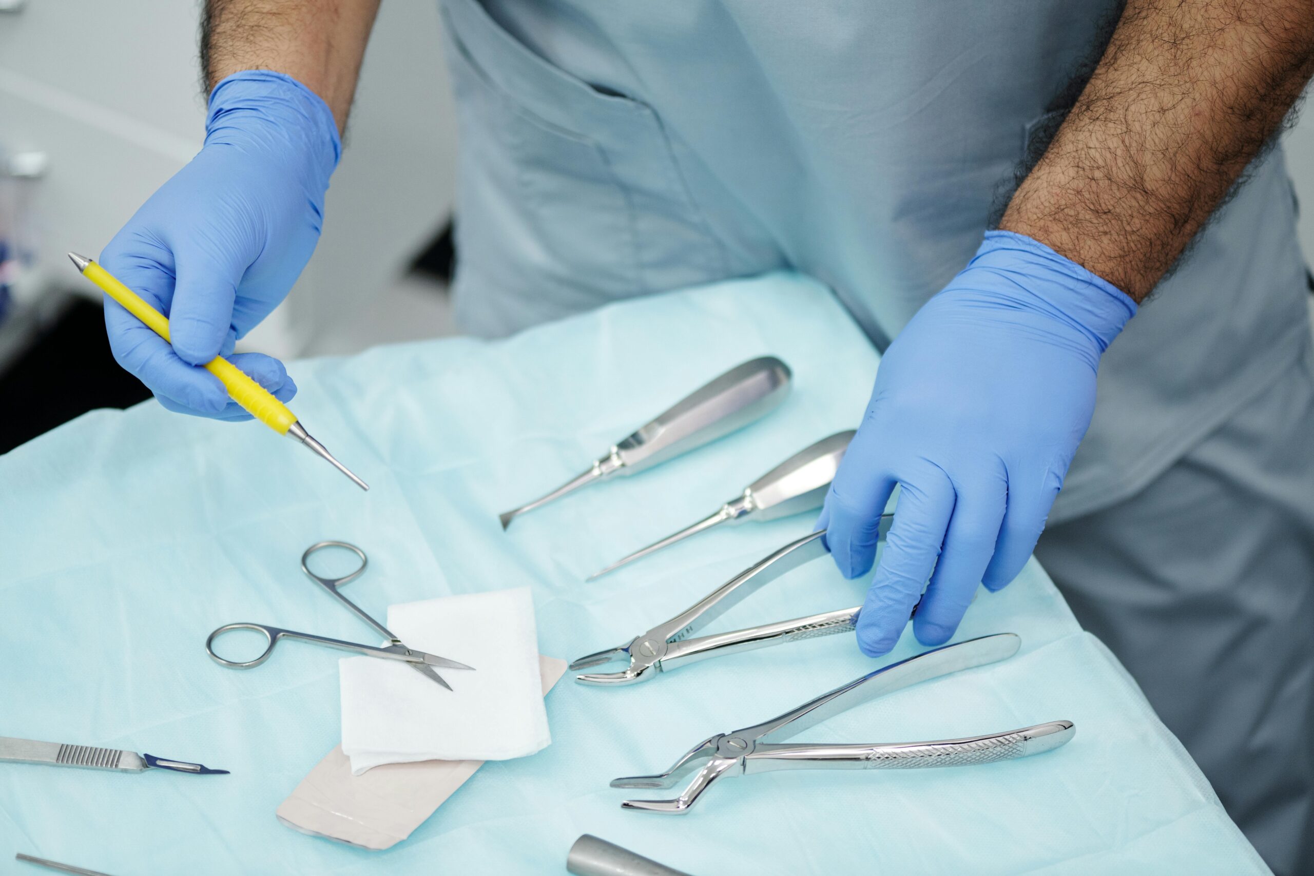 Close-up of a dental professional's hands with tools and gloves in a clinic setting.